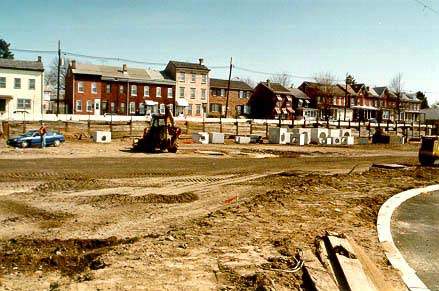 Looking east to homes on adjacent Lamberton Road, a front end loader clears dirt from a section of t